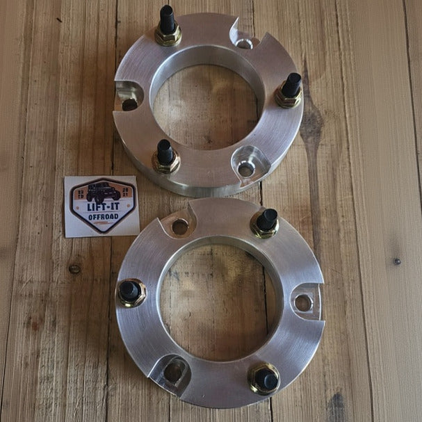 Two metallic wheel spacers on a wooden surface with a 'LIFT IT' label.
