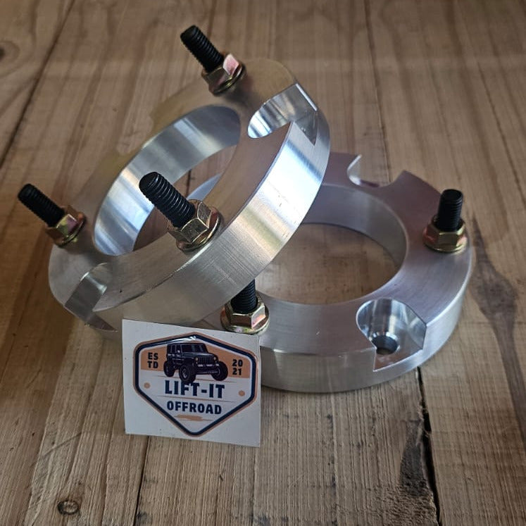 Metallic automotive front strut spacers on a wooden surface with a visible brand label.