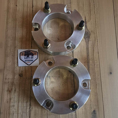 Two metallic wheel spacers on a wooden surface with a 'LIFT IT' label.
