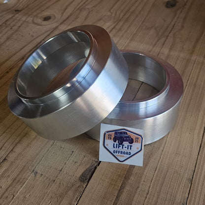 Two aluinium coil spacers on a wooden surface with a 'Lift-It' brand label.